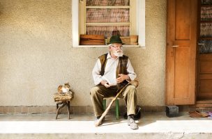 Old man reading the newspaper in front of his house